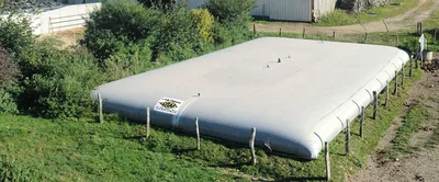 Cisterna flexible para purines instalada sobre postes de madera en una explotación ganadera