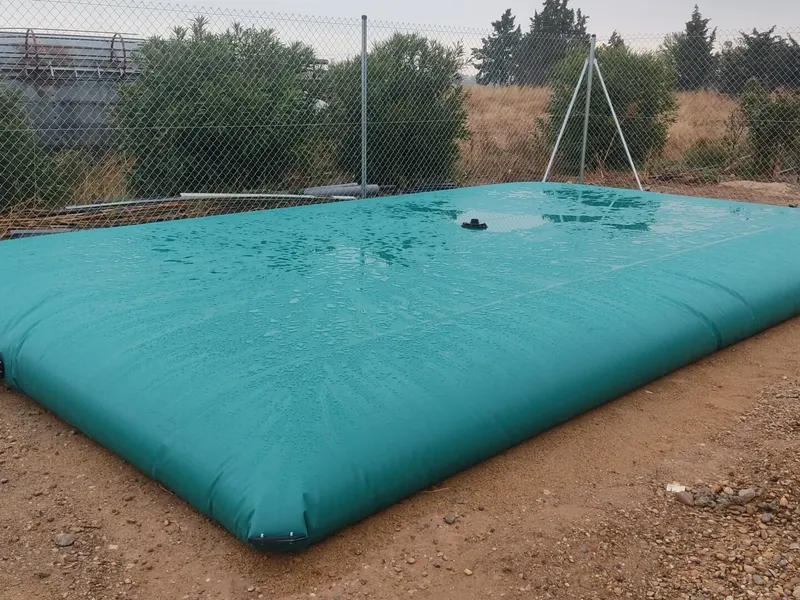 Depósito flexible lleno de agua instalado en una parcela vallada con válvula de salida