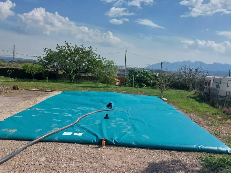 Depósito flexible para agua de riego instalado en una finca con la montaña al fondo