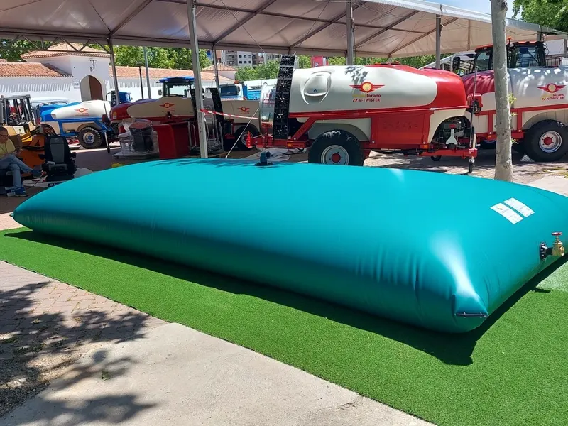 Depósito flexible para agua expuesto junto a maquinaria agrícola en una feria