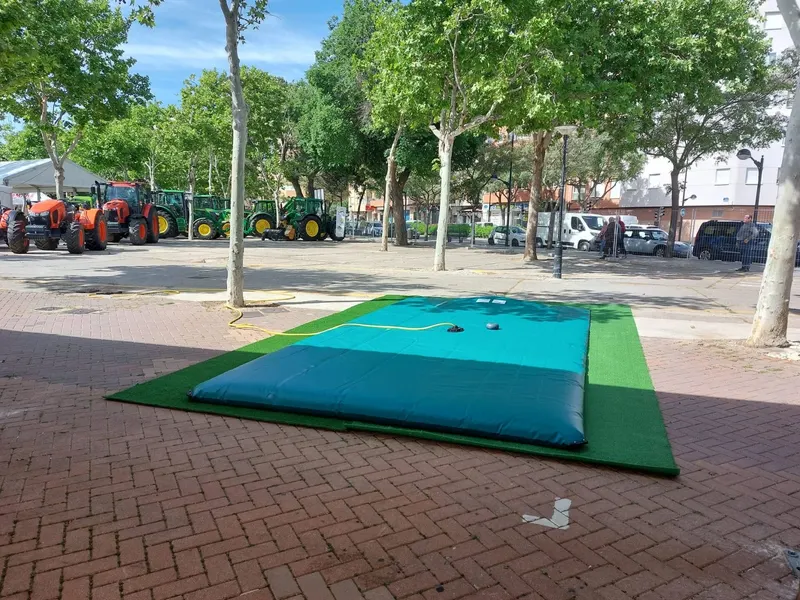 Depósito flexible para agua expuesto en una plaza junto a tractores en una feria agrícola