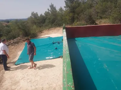 Instalación de un depósito flexible para agua desplegándose en una finca de montaña